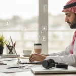 موظف سعودي يعمل عن بُعد على حاسوبه المحمول في مكتبه، مستفيدًا من بيئة عمل مرنة تدعم التوطين والتقنية الحديثة.
